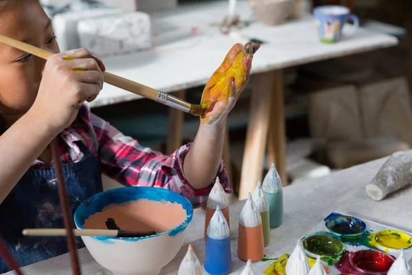 Menina pintando sua mão com pincel de tinta — Fotografia de Stock