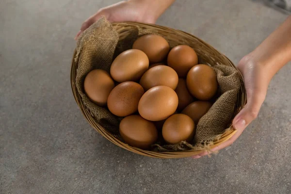 Mulher segurando cesta com ovos castanhos — Fotografia de Stock