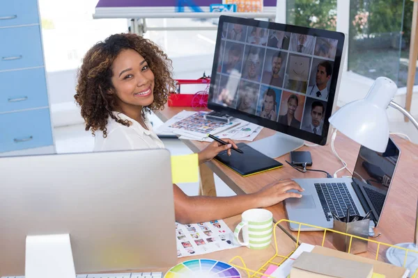 Portrait of female executive working over graphic tablet at her desk in office