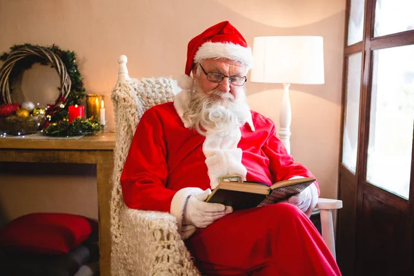 Santa claus lezing roman in woonkamer — Stockfoto