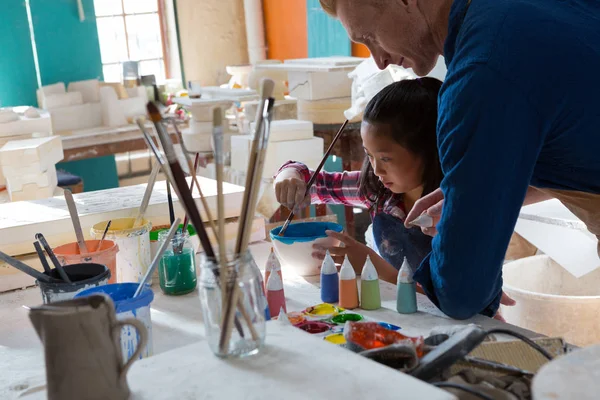 Hombre alfarero ayudar a chica a pintar tazón — Foto de Stock