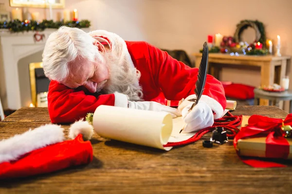 Санта Клаус спит за столом, когда пишет письмо с пером — стоковое фото