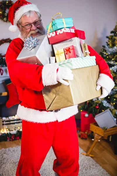 Weihnachtsmann hält Stapel von Geschenken zu Hause — Stockfoto