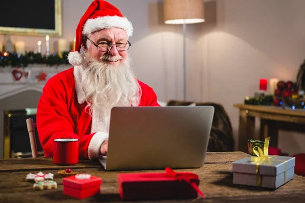 Santa Claus pomocí přenosného počítače na stole — Stock fotografie