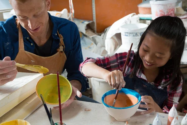 Male potter and girl painting bowl — Stock Photo, Image