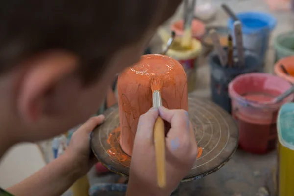 Хлопчик малює чашу в керамічному магазині — стокове фото