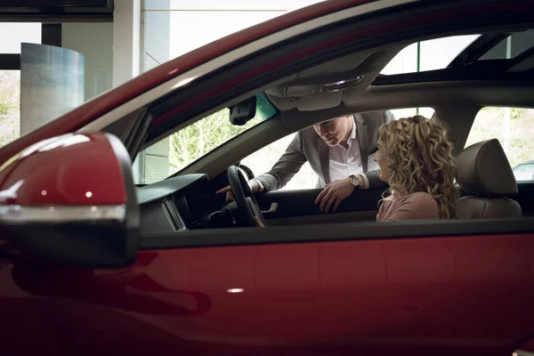 Säljare hjälpa kvinnlig kund i bil — Stockfoto