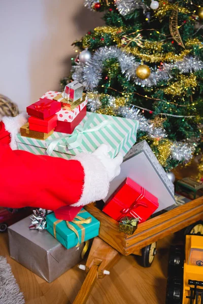 Weihnachtsmann hält Geschenke auf Holzwagen — Stockfoto