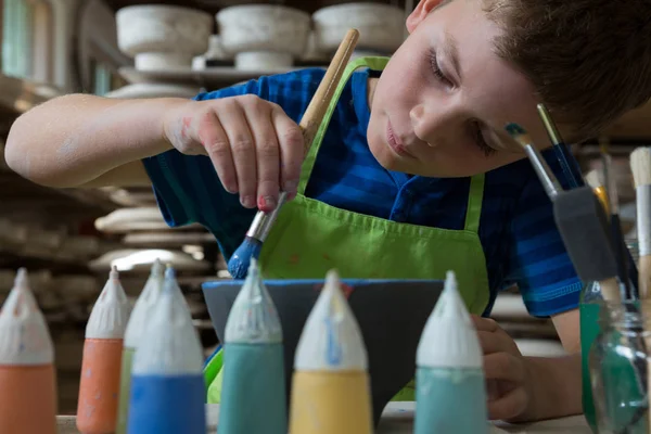 Ragazzo che dipinge una ciotola in negozio di ceramica — Foto Stock