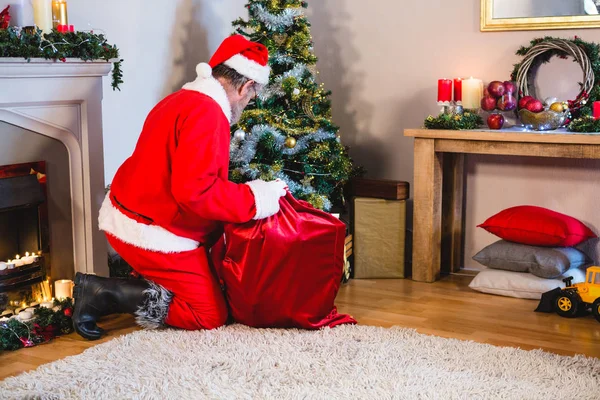 Santa claus att sätta presenterar i christmas väska — Stockfoto