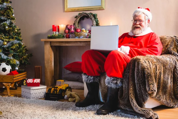 Weihnachtsmann sitzt und benutzt Laptop — Stockfoto