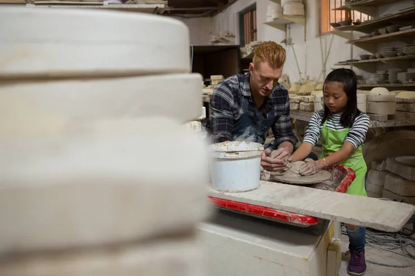 Male potter assisting his daughter in making a pot — Stock Photo, Image