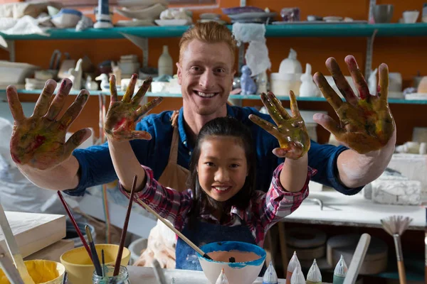 Potter and girl showing their painted hands — Stock Photo, Image