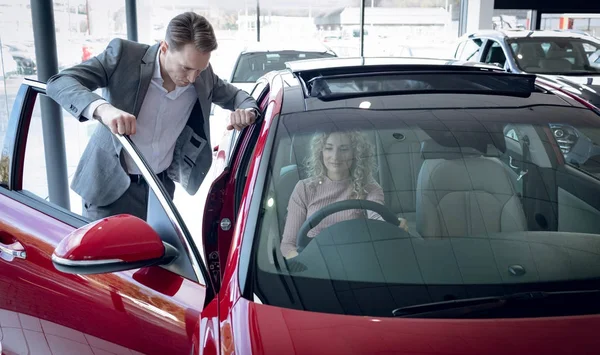 Salesman standing by customer sitting in car — Stock Photo, Image