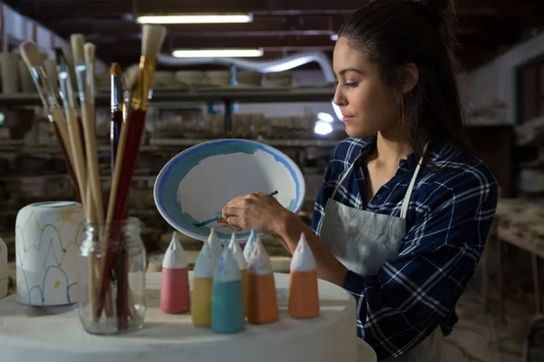 Potter decorating bowl with paint brush — Stock Photo, Image