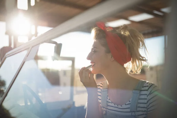 Mujer aplicando lápiz labial en un coche — Foto de Stock