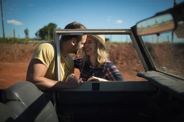 Couple romancing together behind a car — Stock Photo, Image