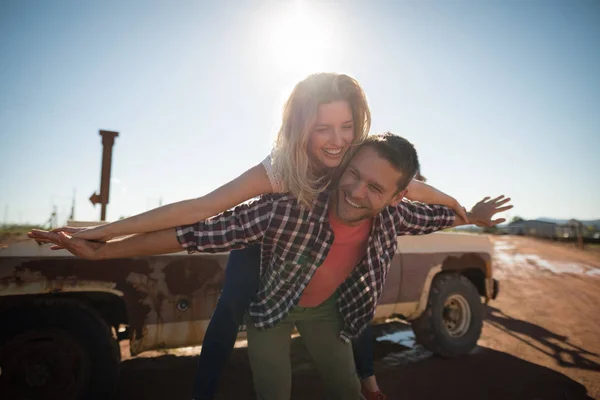 Man giving a piggyback ride to woman — Stock Photo, Image