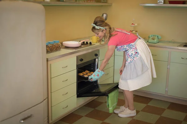 Kelnerka wprowadzenie babeczki w piekarniku — Zdjęcie stockowe