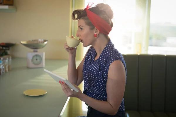 Vrouw met koffie tijdens het gebruik van digitale tablet — Stockfoto