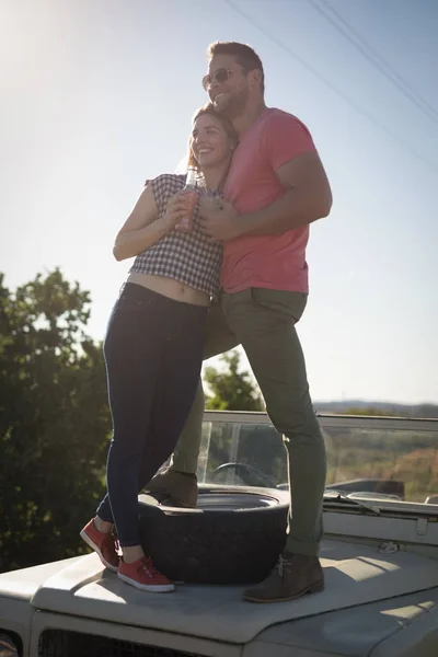 Couple prenant un verre sur le capot de la voiture — Photo