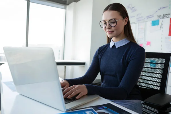 Female executive using laptop at desk — Stock Photo, Image