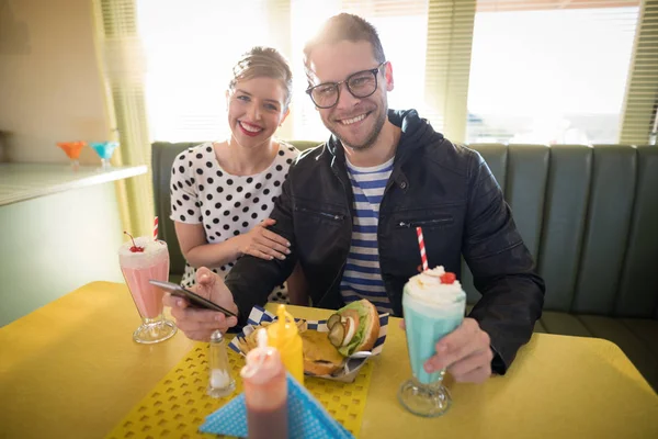 Pareja usando teléfono móvil en restaurante — Foto de Stock