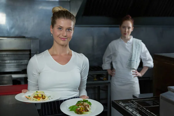 Vrouwelijke chef-koks houden van voedsel platen — Stockfoto