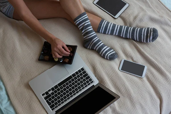 Mujer teniendo chocolates en la cama — Foto de Stock