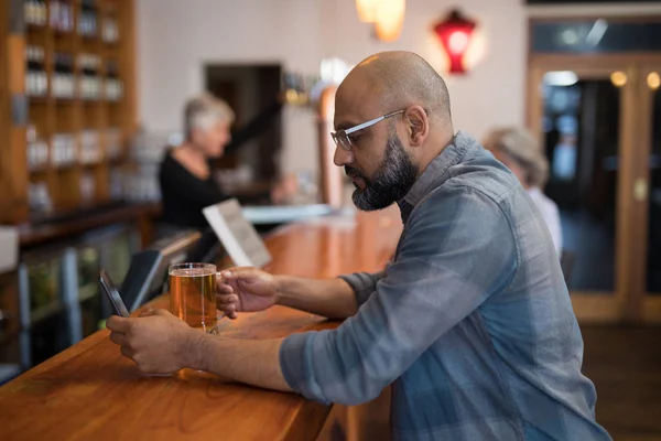 Człowiek za pomocą telefon mając beer — Zdjęcie stockowe