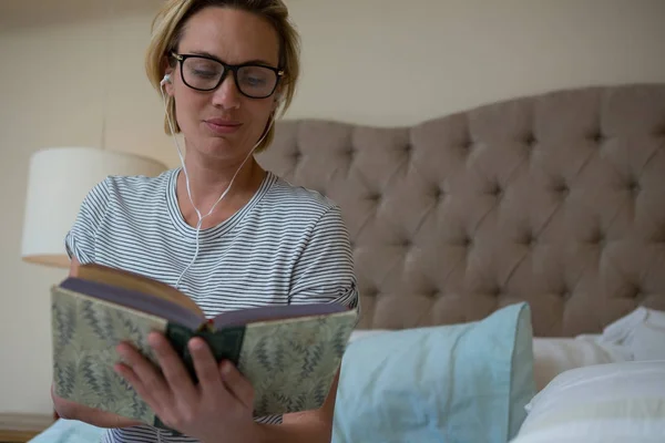 Žena čte knihy během poslechu hudby — Stock fotografie