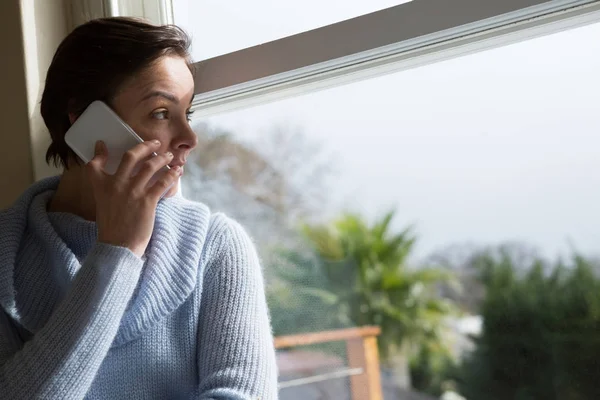 Woman talking on phone near window — Stock Photo, Image