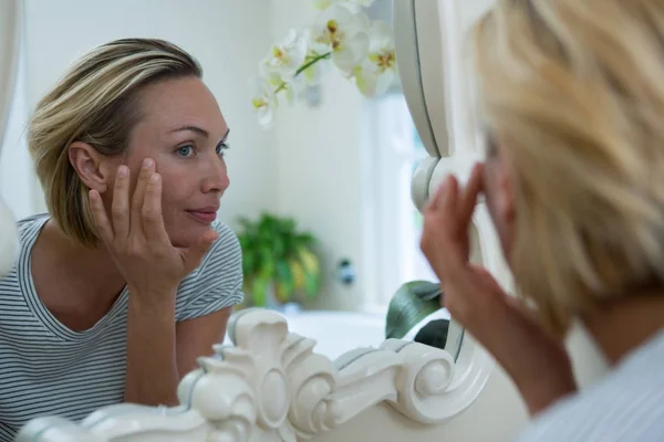 Женщина смотрит в зеркало ванной комнаты — стоковое фото