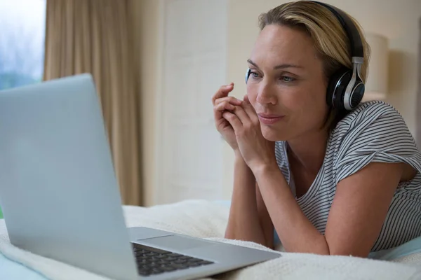 Frau benutzt Laptop beim Musikhören — Stockfoto