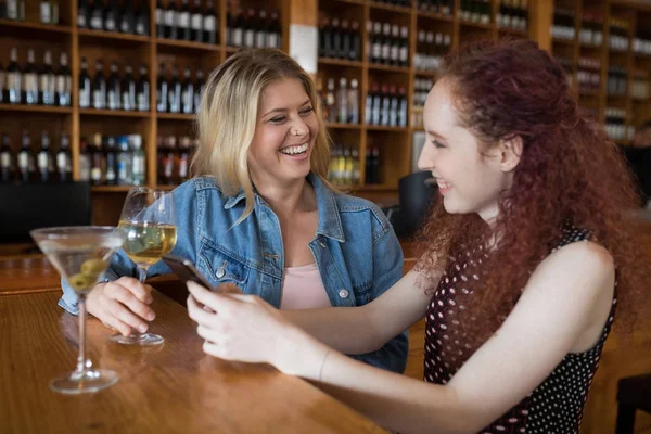 Amigos femeninos usando el teléfono mientras toman bebidas —  Fotos de Stock