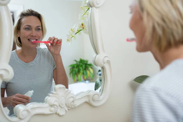 Spiegelbild einer Frau beim Zähneputzen — Stockfoto