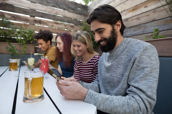 Vrienden met behulp van de mobiele telefoon in bar — Stockfoto