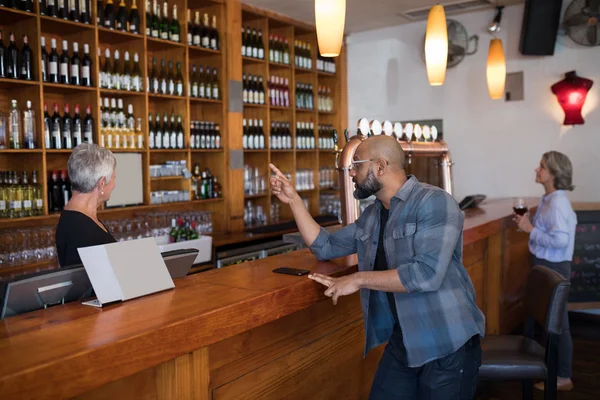 Man ordering a wine bottle at bar counter — Stock Photo, Image