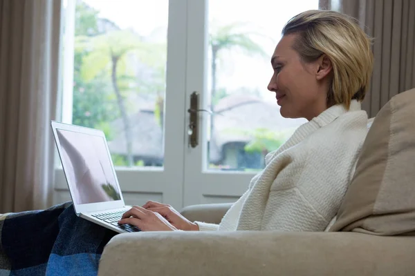 Красива жінка використовує ноутбук на дивані — стокове фото