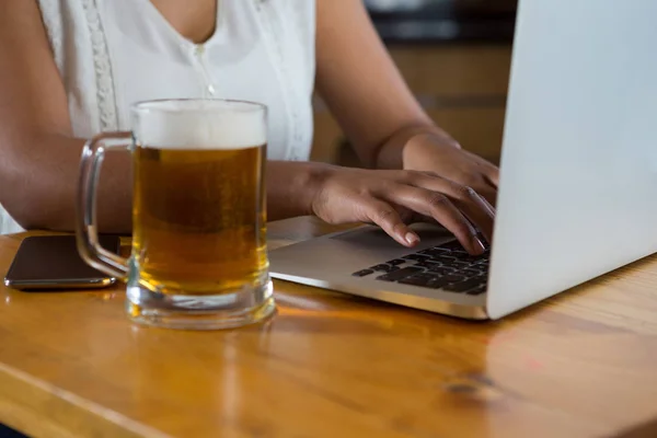 Frau benutzt Laptop an Bar — Stockfoto