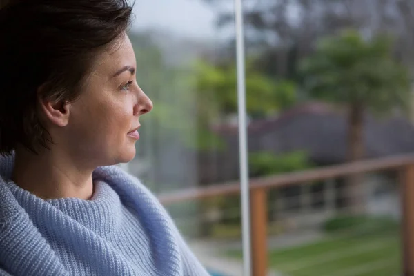 Doordachte vrouw op zoek door raam — Stockfoto