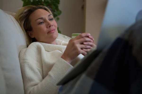 Eftertänksam kvinna ha kaffe på soffa — Stockfoto