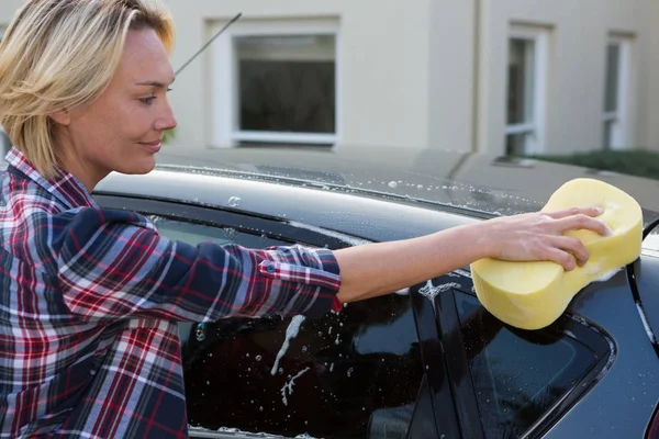 Frau putzt ihr Auto mit Schwamm — Stockfoto
