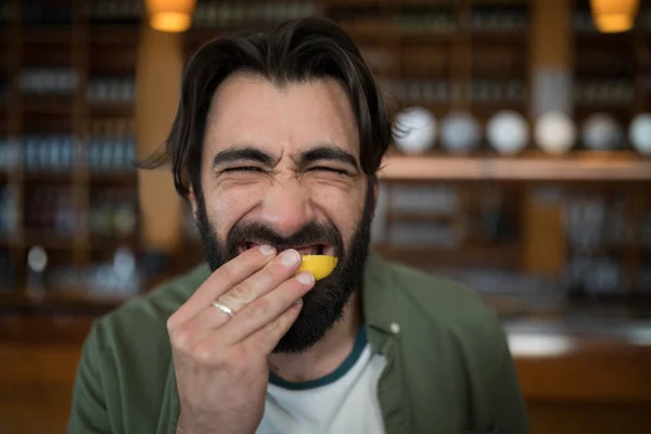 Man biting into lemon wedge