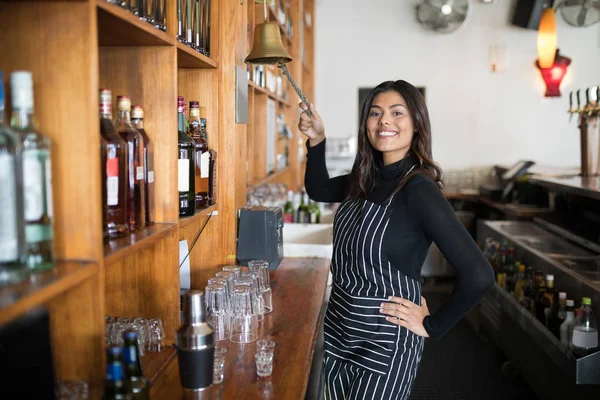 Smiling waitress ringing bell at counter — Stock Photo, Image