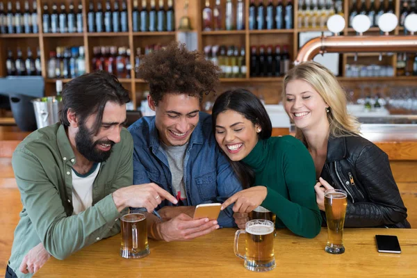 Vrienden met behulp van de telefoon terwijl het hebben van bier — Stockfoto