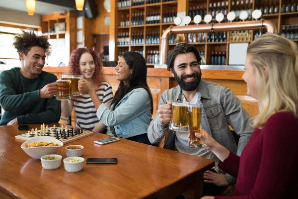 Vrienden roosteren glas bier in staaf — Stockfoto