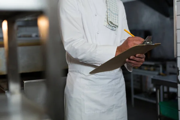 Мужчина-шеф-повар пишет заказ на планшете — стоковое фото
