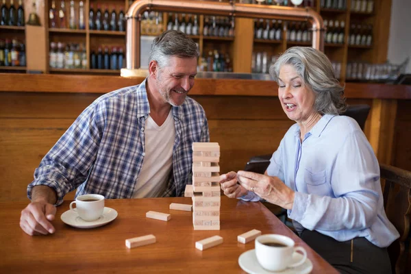 Senior friends playing jenga game on table — Stock Photo, Image