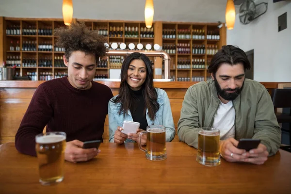 Vrienden met behulp van mobiele telefoon op tafel — Stockfoto